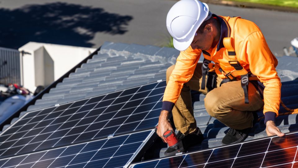 Solar panel technician with drill installing solar panels 1